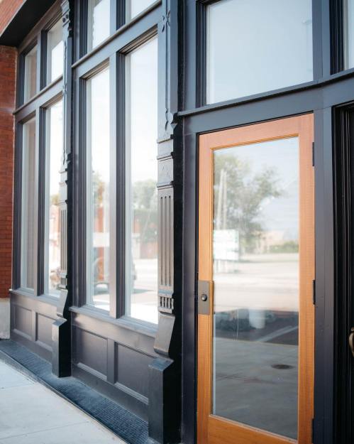A close-up of a storefront featuring large windows and a wooden door with decorative elements.