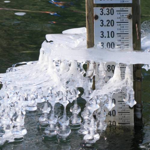 A water gauge partially submerged in water, with bubbles and foam forming around it.