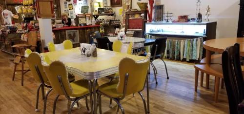 A retro diner interior with yellow and black chairs, a vintage counter, and various nostalgic decor items.