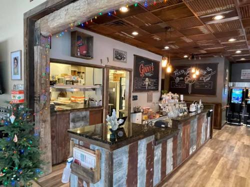 Cozy restaurant interior with a wooden counter, festive lights, and a glimpse of the kitchen area.
