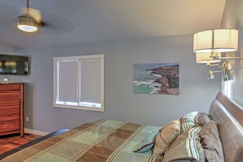 Cozy bedroom featuring a bed, dresser, wall art, and a TV, with natural light from two windows.