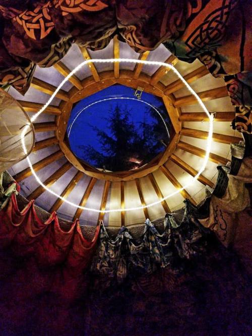 View from inside a yurt, showcasing a circular wooden frame and colorful fabric drapes against a night sky.