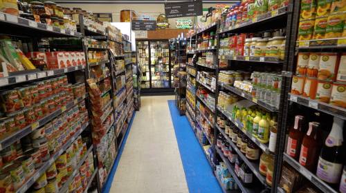 A grocery store aisle filled with various canned goods, sauces, and beverages on both sides.