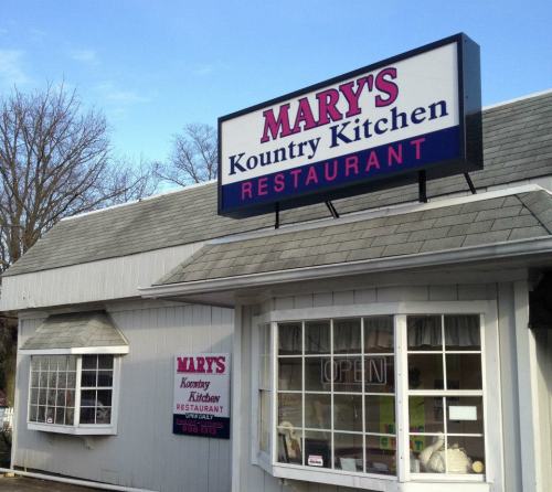 Sign for Mary's Kountry Kitchen restaurant, featuring a bright blue sky and a welcoming "OPEN" notice in the window.