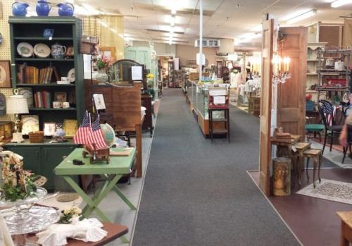 A spacious antique shop aisle lined with various vintage items, furniture, and decor on display.