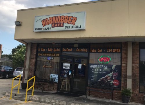 Exterior of Hobnobber Cafe, featuring a sign, open neon light, and large windows displaying menu items and specials.