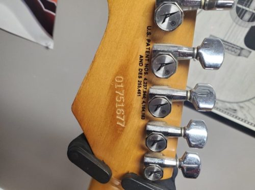 Close-up of a guitar headstock showing tuning pegs and patent numbers engraved on the wood.