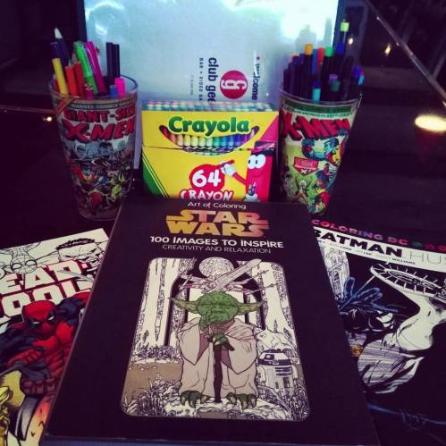 A collection of coloring supplies, comic books, and a Star Wars inspiration book on a table.