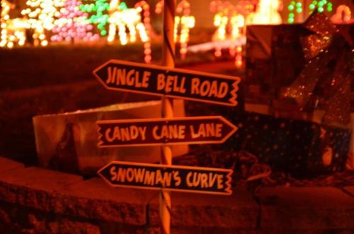 Three festive signs point to "Jingle Bell Road," "Candy Cane Lane," and "Snowman's Curve," surrounded by holiday lights.