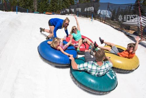 A group of people enjoying snow tubing on a sunny day, laughing and having fun on colorful inflatable tubes.