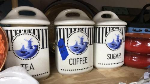Three ceramic canisters labeled "TEA," "COFFEE," and "SUGAR," featuring blue windmill designs and black stripes.