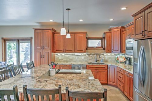 Modern kitchen with wooden cabinets, granite countertops, and stainless steel appliances, featuring a large island and bar seating.