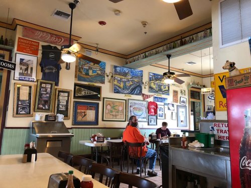 Cozy restaurant interior with colorful wall art, tables, and a counter, featuring a casual dining atmosphere.