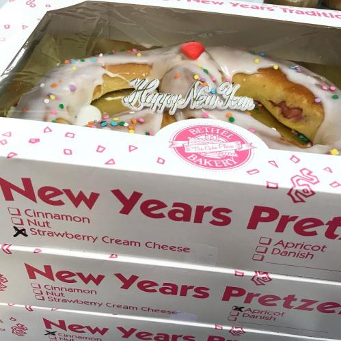 A box of New Year's pretzels with colorful sprinkles and a "Happy New Year" decoration on top.