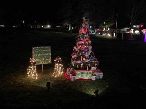 A decorated Christmas tree with lights and ornaments, next to a sign reading "Quarantine" and festive displays in the background.