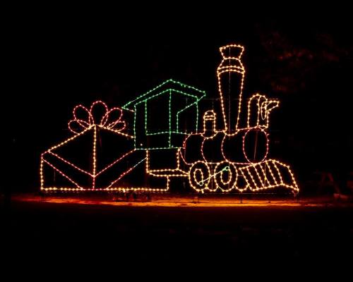 A colorful train made of lights, with a gift box, set against a dark night background.