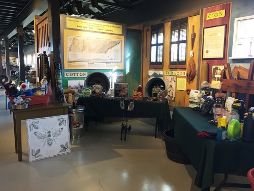 Display of agricultural items and historical artifacts in a museum setting, featuring cotton, corn, and tobacco themes.