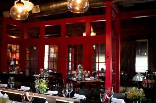 A cozy restaurant interior featuring red walls, wooden tables, and elegant lighting, creating a warm atmosphere.
