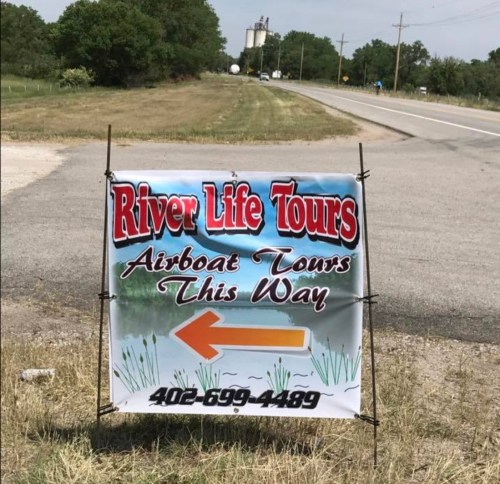 Sign for River Life Tours advertising airboat tours, with an arrow pointing left and a contact number.