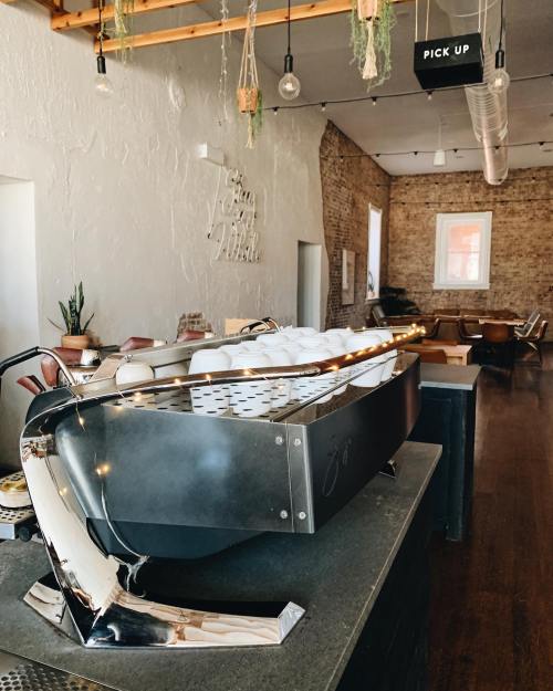 A sleek, modern coffee bar with a unique boat-shaped design, surrounded by stylish seating and warm lighting.