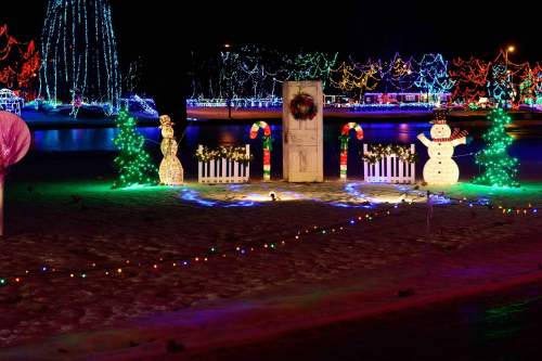 A festive scene with colorful holiday lights, a snowman, and a decorated door surrounded by candy canes and trees.