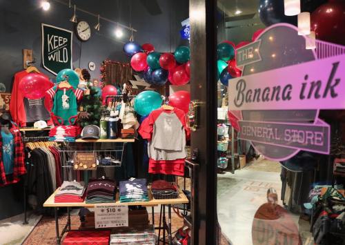 A colorful store display featuring clothing, balloons, and a sign for "Banana Ink General Store."