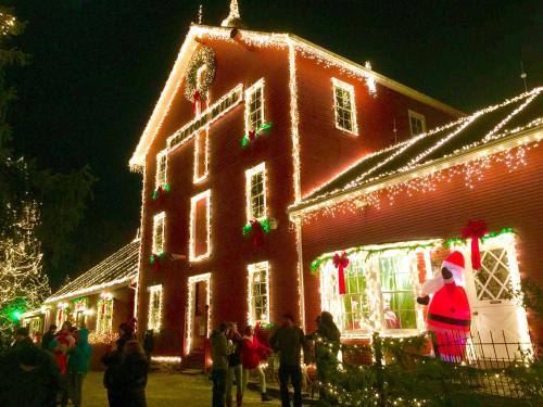 A festive building adorned with colorful Christmas lights and decorations, featuring a Santa figure in the window.