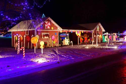 A festive display featuring a gingerbread house with colorful candy decorations and bright lights at night.