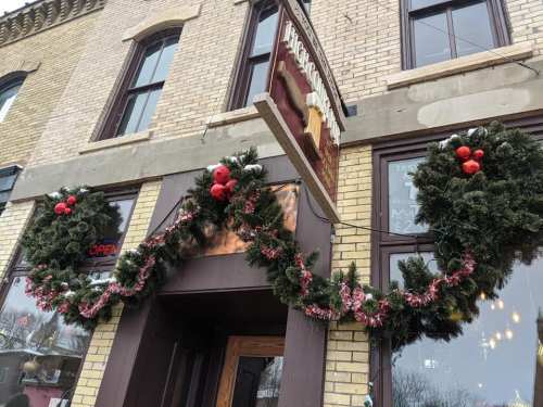 A festive storefront decorated with wreaths and red ornaments for the holiday season.