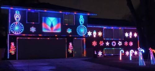 A house decorated with colorful Christmas lights, featuring snowmen, candy canes, and festive patterns.