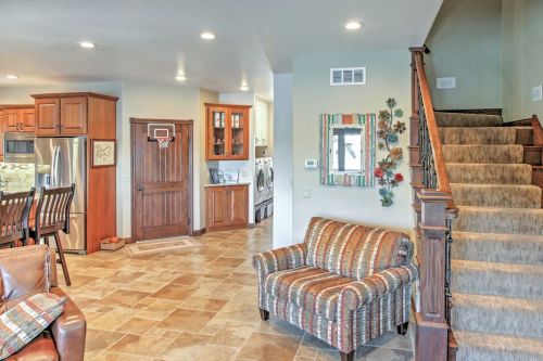 Cozy living space featuring a striped sofa, kitchen area, laundry room, and staircase with decorative wall art.