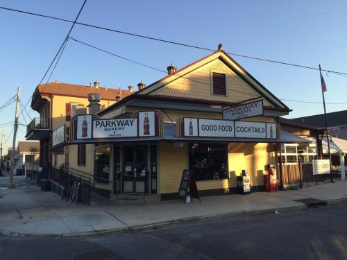 A yellow building with a sign reading "Parkway Bakery" and "Good Food, Cocktails" in a sunny street setting.
