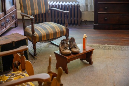 A pair of brown shoes on a small wooden table in a cozy room with a striped chair and wooden furniture.