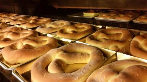 Freshly baked pretzels arranged on trays inside an oven, golden brown and steaming.