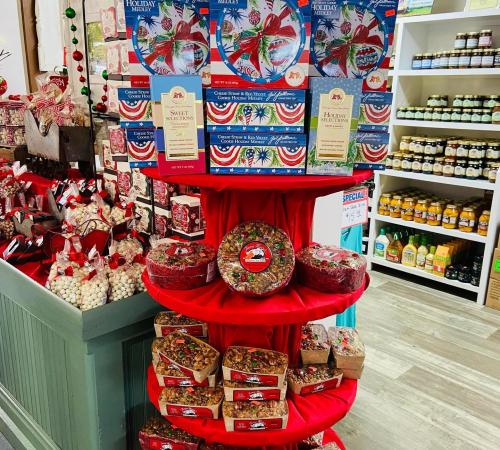 A festive display of holiday treats, including boxes of snacks and jars, arranged on a red table in a shop.