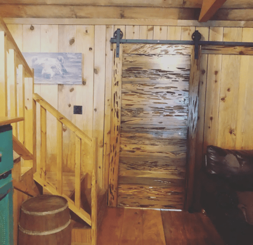 A cozy wooden interior featuring a staircase, a sliding barn door, and rustic decor.