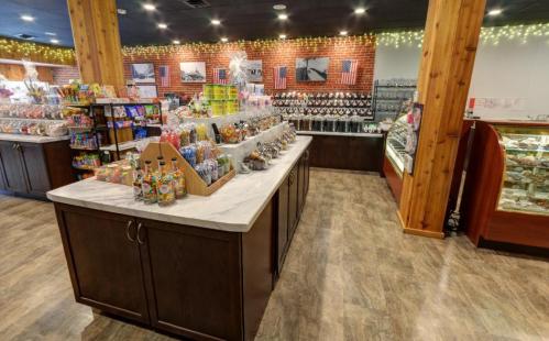A colorful candy shop interior with shelves of sweets, a display case, and festive decorations.