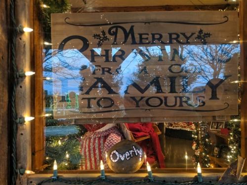 A festive sign reads "Merry Christmas to your family," framed by holiday lights and decorations.