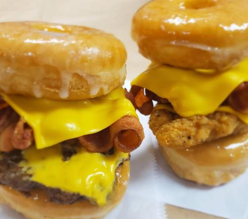 Two stacked burgers featuring glazed donut buns, melted cheese, crispy bacon, and fried chicken.