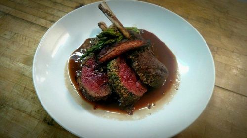 A gourmet dish featuring tender lamb chops, asparagus, and a rich sauce, elegantly plated on a white dish.