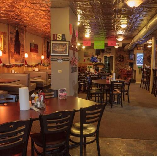 Cozy restaurant interior with wooden tables, festive decorations, and warm lighting.