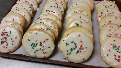 A tray of frosted cookies decorated with red and green sprinkles, arranged in neat rows.