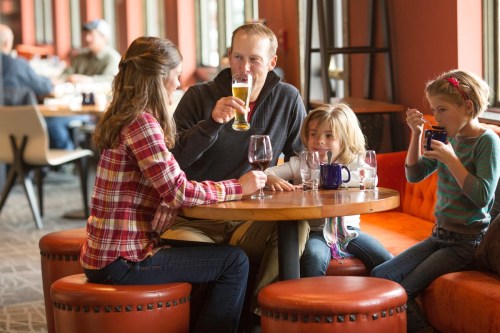 A family enjoys drinks at a cozy restaurant table, with two adults and two children engaged in conversation.