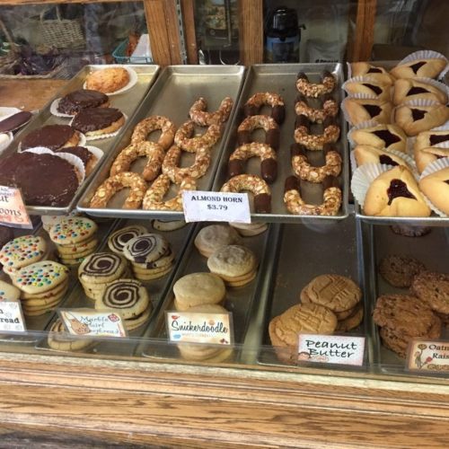 A display case filled with various cookies and pastries, including almond horns, snickerdoodles, and decorated cookies.