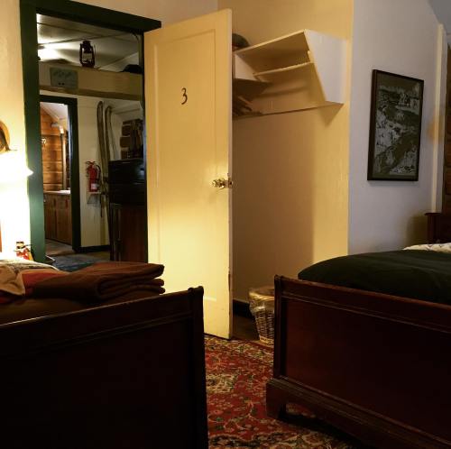 A cozy room with a bed, a door labeled "3," and a glimpse of a kitchen area in the background.