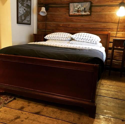 Cozy bedroom featuring a wooden bed, patterned pillows, and rustic decor with wooden walls and floor.