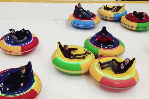 Aerial view of colorful bumper cars on ice, with people enjoying a fun activity in a rink.