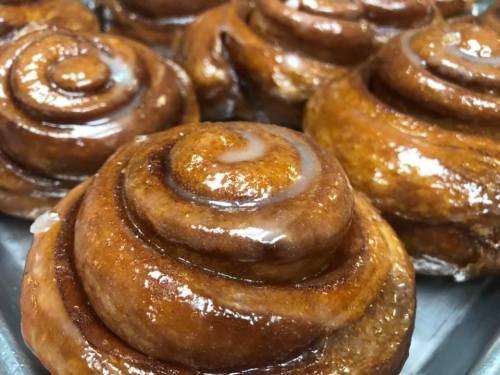 Close-up of freshly baked cinnamon rolls with a glossy glaze, arranged on a tray.
