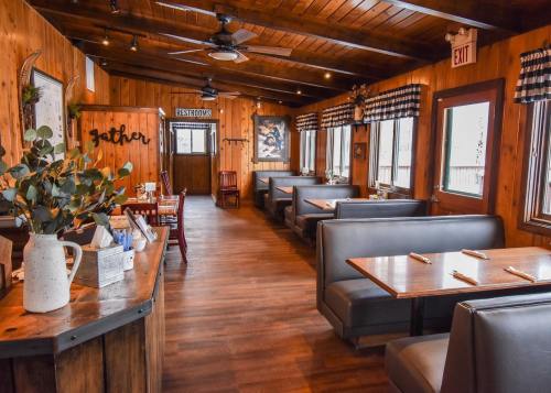 Cozy wooden restaurant interior with booths, tables, and rustic decor, featuring warm lighting and a welcoming atmosphere.