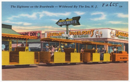 Vintage postcard depicting a lively boardwalk scene in Wildwood, NJ, featuring amusement stalls and colorful attractions.